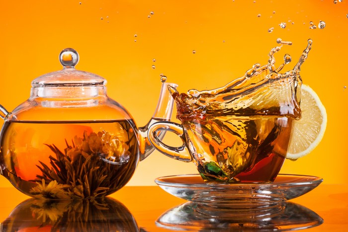 Tea splash in cup with lemon and teapot