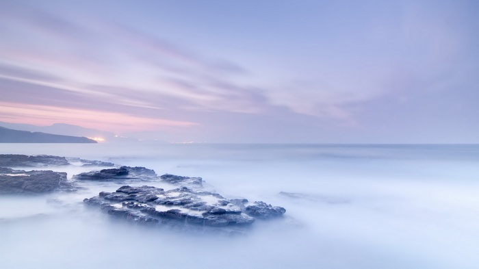 Rocky coastline with misty ocean and pastel sky