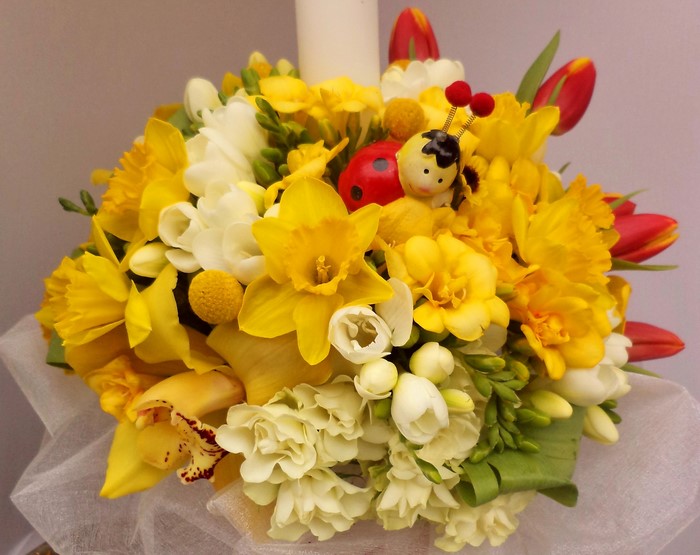 Yellow and white floral arrangement with ladybug and bee decorations