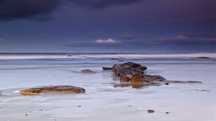 Long exposure of rocks on a beach at dusk