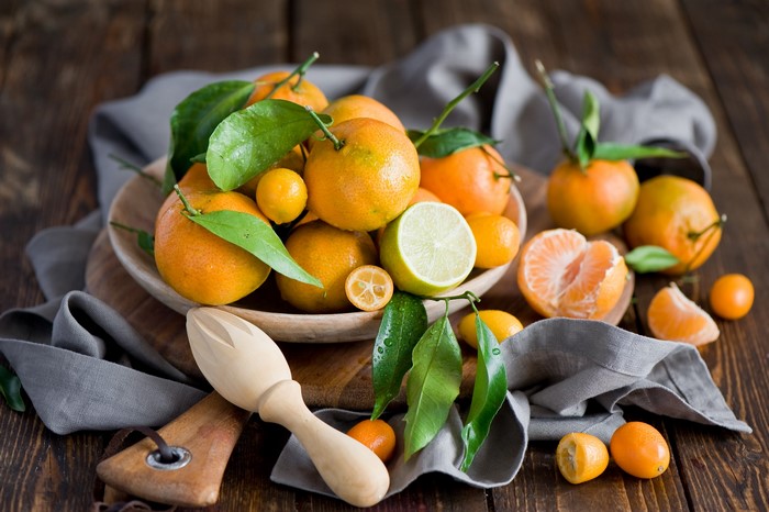 Citrus fruits on a wooden table with a juicer