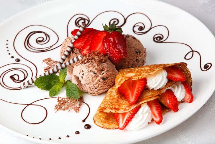 Chocolate ice cream with strawberries and a crepe on a plate