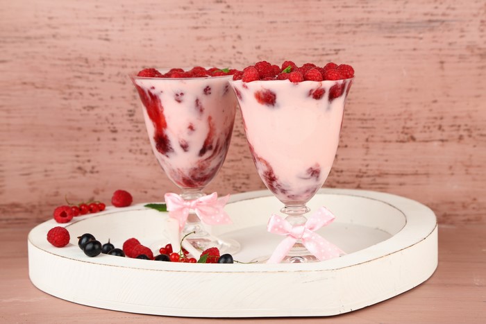 Raspberry desserts in stemware with berries on tray