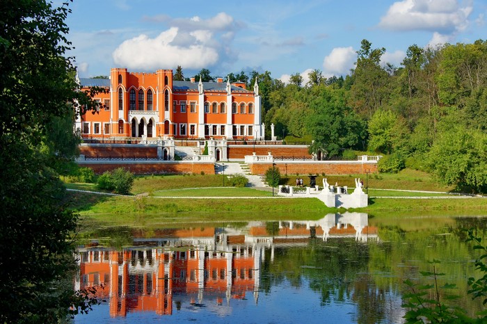 Orange castle with white accents reflected in a pond