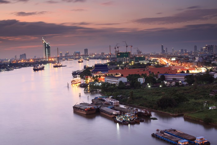 Bangkok Riverfront at Dusk with Boats and Cityscape