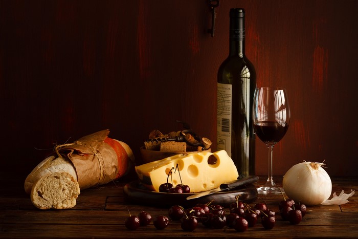 Still life with wine, cheese, bread, cherries, and onion