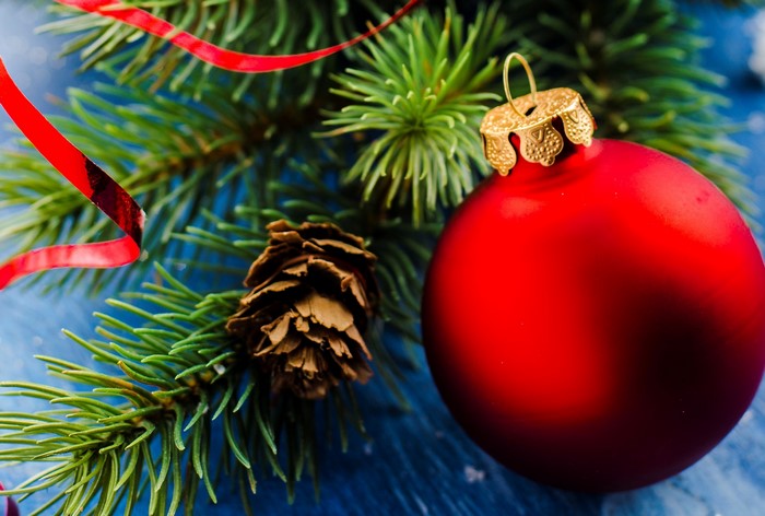 Christmas ornament on a pine branch with pine cone and ribbon