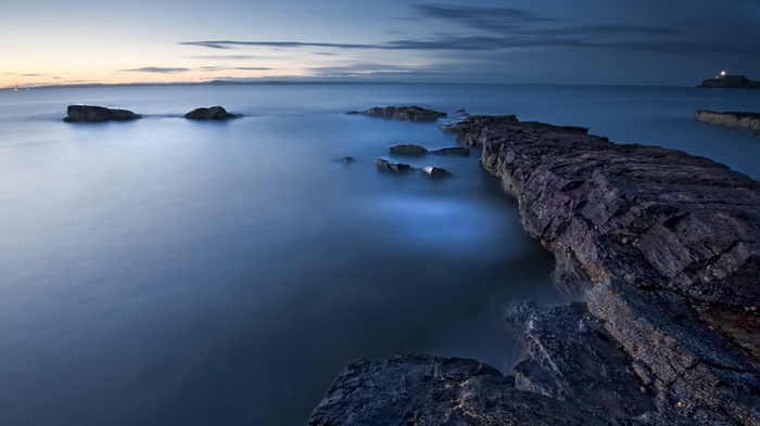 Rocky coastline at dusk with calm water