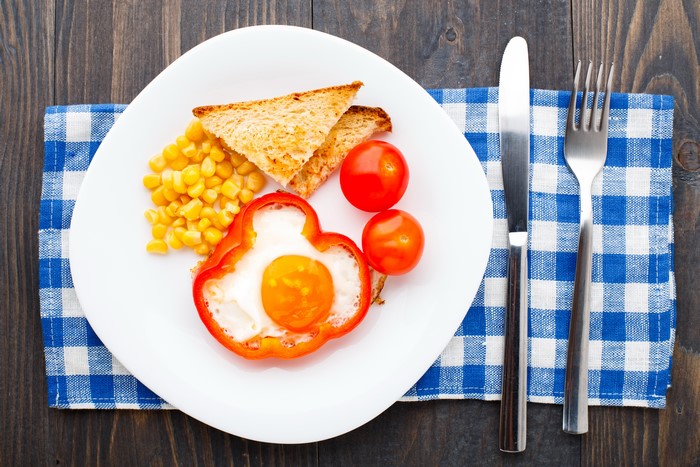 Breakfast plate with egg in pepper, toast, corn, and tomatoes
