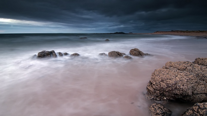 Stormy sky over a rocky beach with long exposure water