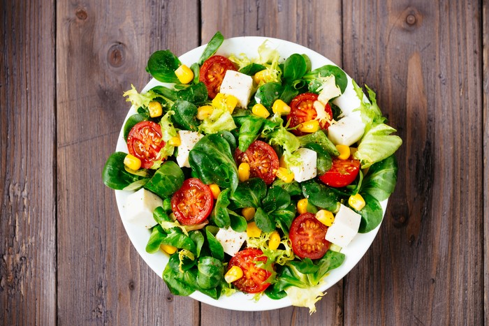 Salad with tomatoes, corn, and cheese on a plate