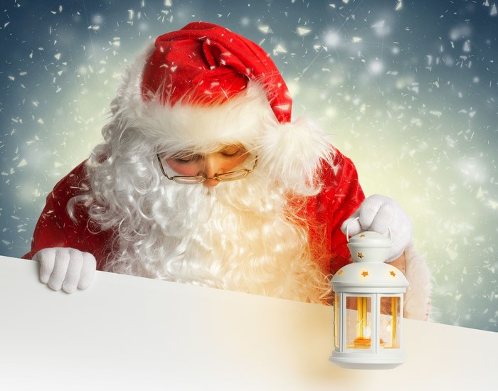 Santa Claus holding a lantern with a blank sign