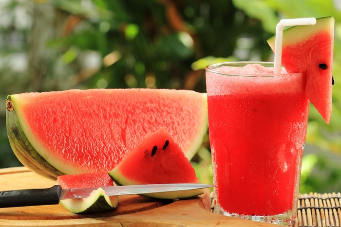Watermelon juice with watermelon slices and a knife