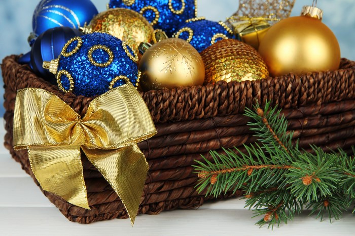 Christmas ornaments in a wicker basket with a bow and pine branch
