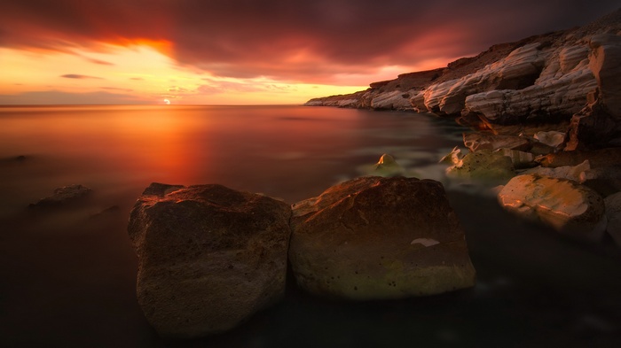 Sunset over the ocean with rocky coastline