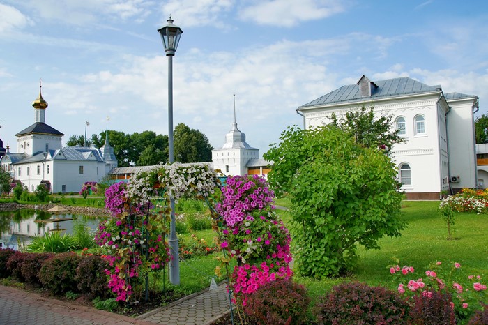 Monastery garden with blooming petunias and white buildings