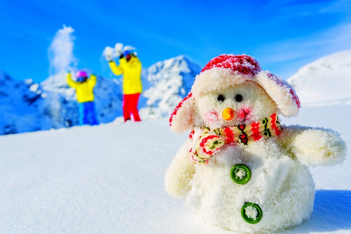 Plush snowman with people playing in snow