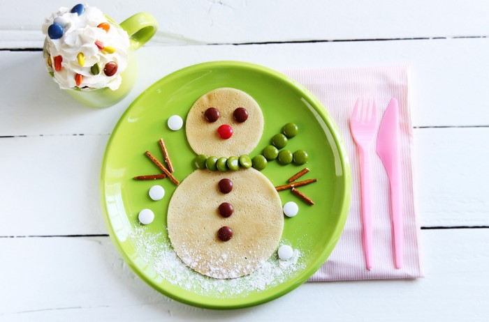 Snowman pancake art with candy and whipped cream