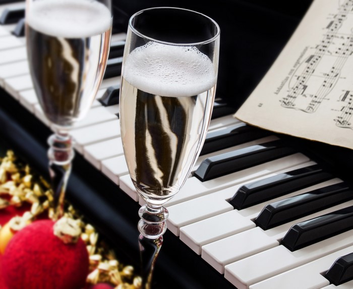 Champagne glasses on a piano with sheet music and ornaments