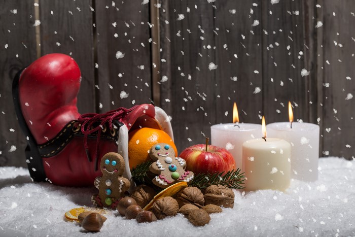 Christmas boot with fruit, cookies, candles, and nuts in snow