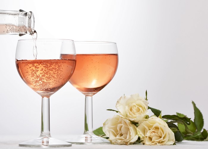 Rose Wine Being Poured into Glasses with Roses