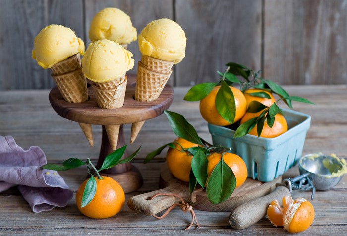 Orange ice cream cones and tangerines on a wooden table