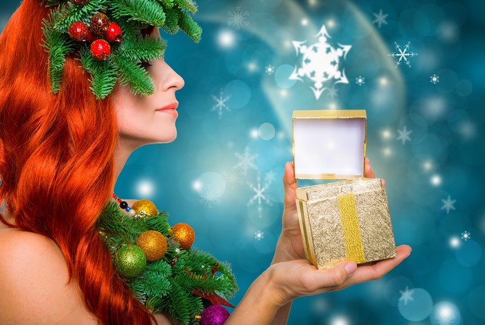 Woman with red hair and Christmas decorations opening a gift