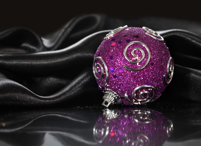 Purple glitter Christmas ornament on black silk