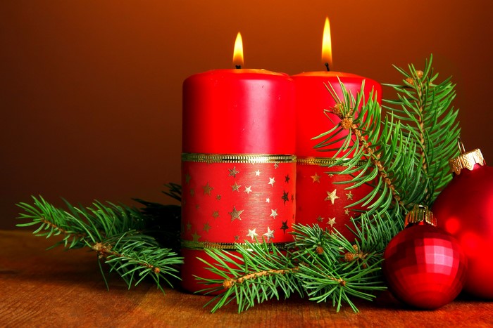 Two red Christmas candles with pine branches and ornaments