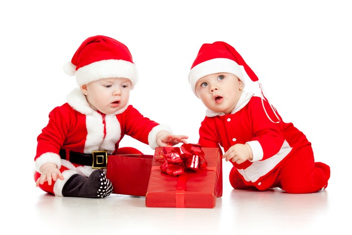 Two infants in Santa costumes with Christmas gifts
