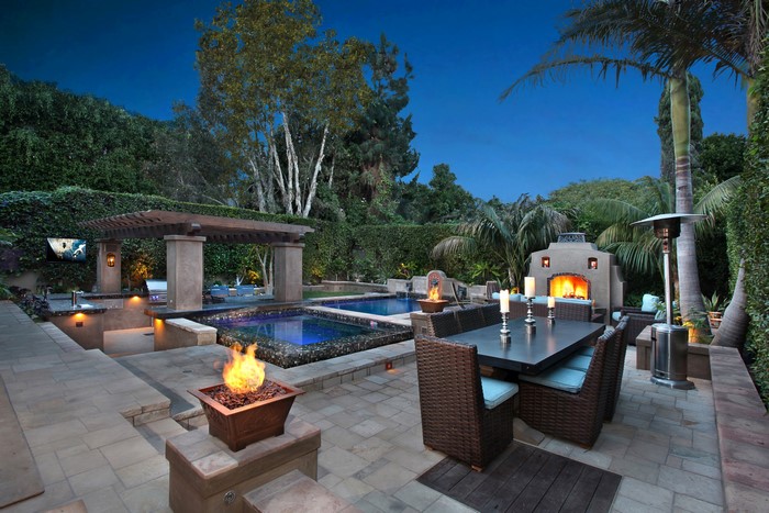 Outdoor patio with pool, spa, dining table, and fireplace