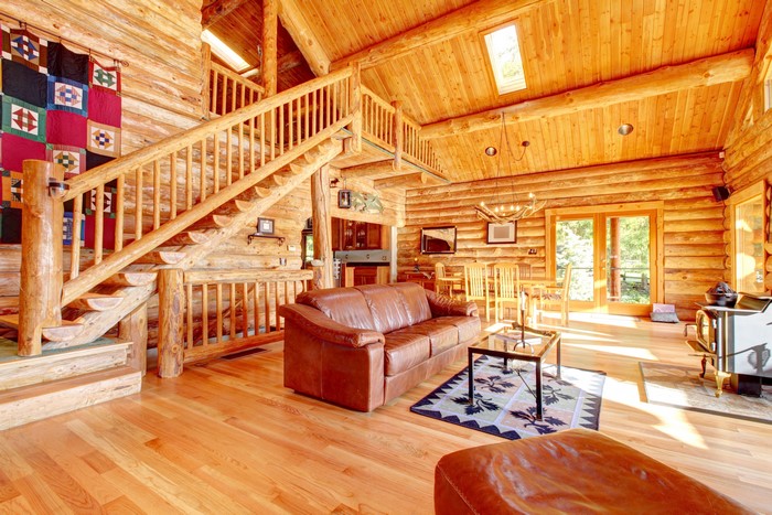 Log cabin interior with living room, stairs, and dining area