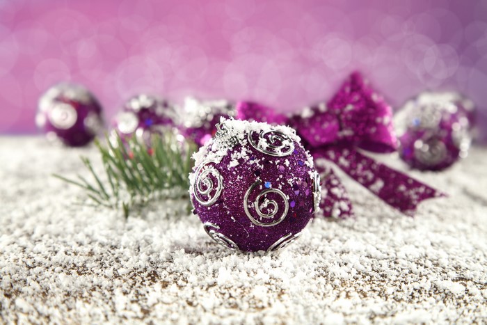 Purple Christmas ornaments with snow and pine needles