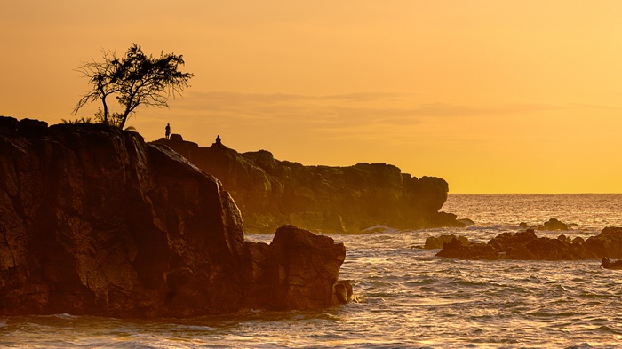 Silhouettes on a rocky coast at sunset