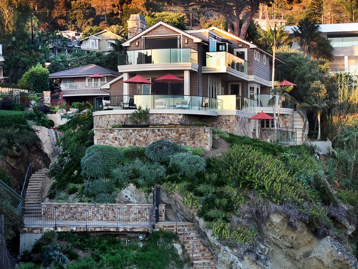 Luxury hillside mansion with stairs and shrubs in Laguna Beach, California