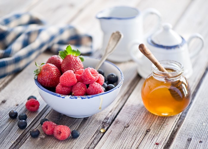 Bowl of berries with honey and pitchers
