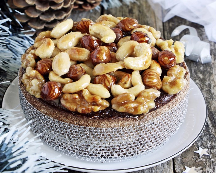 Chocolate cake topped with glazed nuts and decorated with silver ribbon