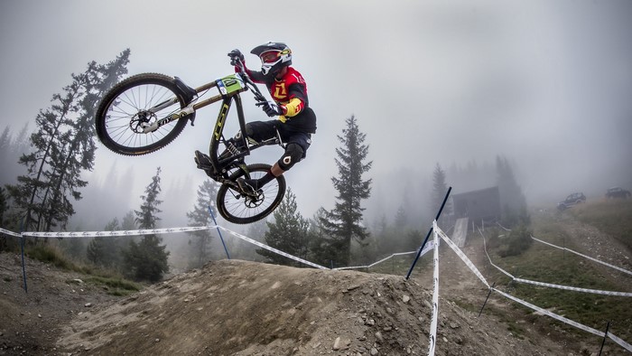Man performing a bicycle jump in a foggy forest