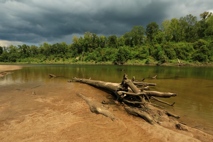 River with fallen tree and stormy sky
