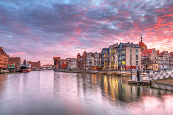 Gdańsk waterfront with historic buildings and a crane at sunset