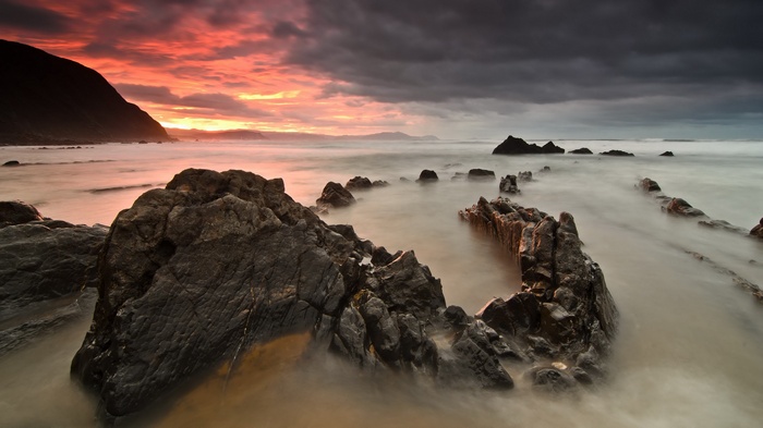Rocky coastline at sunset with dramatic clouds
