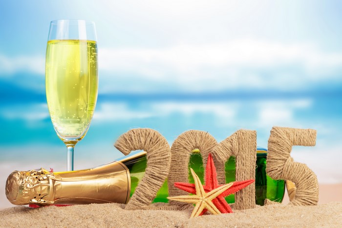 Champagne bottle and glass with 2015 numbers on beach