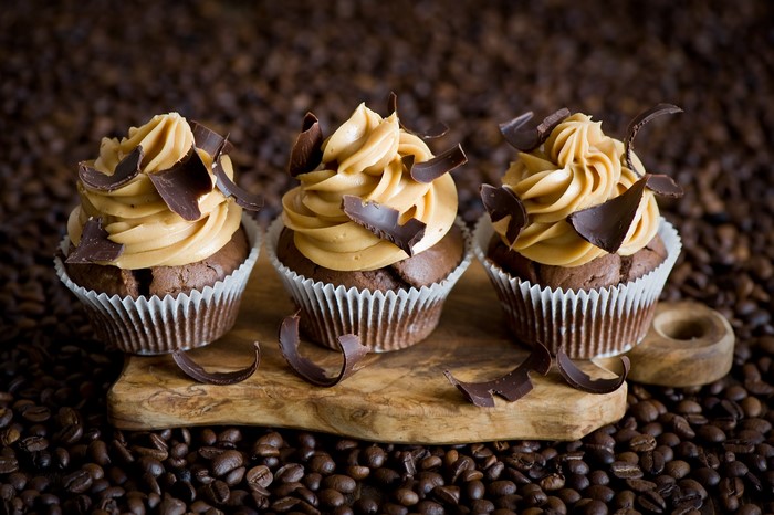 Three chocolate cupcakes with caramel frosting and chocolate shavings