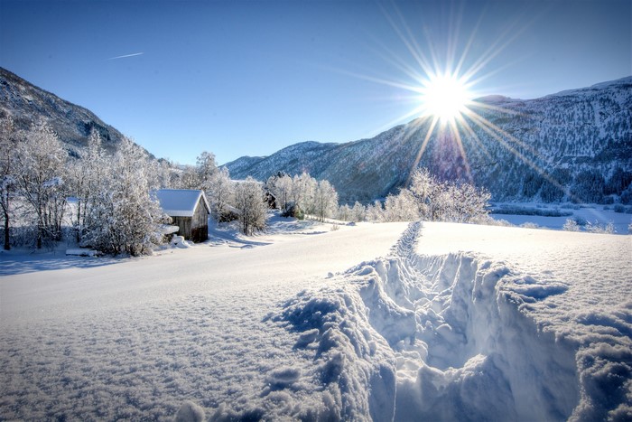 Winter landscape with snow-covered mountains and a wooden cabin