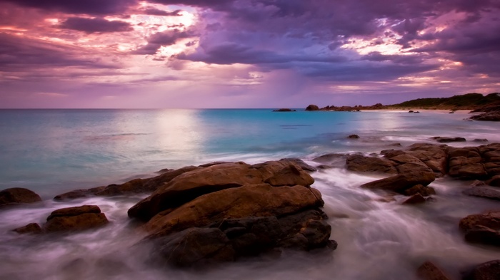 Ocean waves crashing on rocky shore at sunset