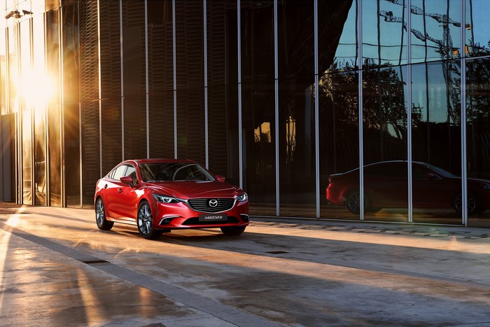 Red 2015 Mazda 6 parked in front of a modern building
