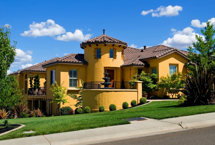 Yellow Mediterranean-style mansion with a fountain and manicured lawn