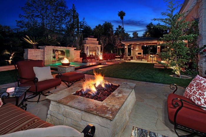 Backyard patio with fire pit and pool at night