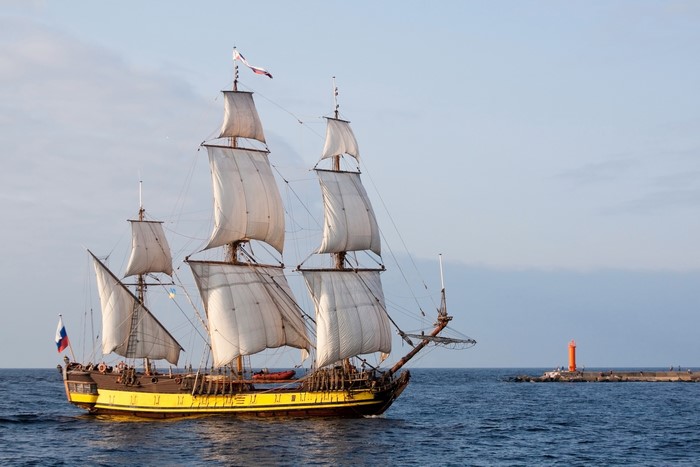 Tall Ship Sailing on the Sea Near a Lighthouse