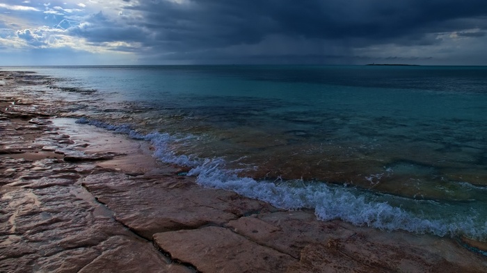 Rocky shoreline with turquoise water and dark clouds
